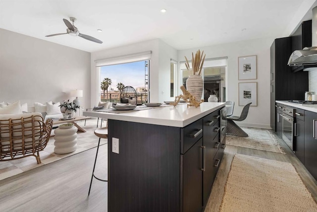 kitchen featuring light wood-style floors, light countertops, a kitchen breakfast bar, and open floor plan