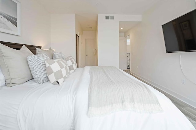 bedroom with visible vents, baseboards, and wood finished floors