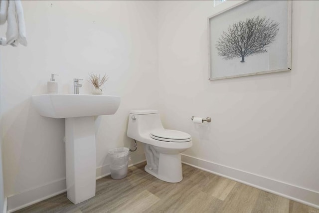 bathroom with toilet, baseboards, and wood finished floors