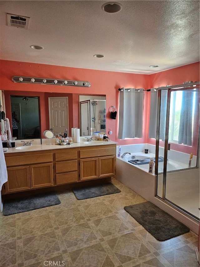 bathroom featuring visible vents, a garden tub, double vanity, a sink, and a stall shower