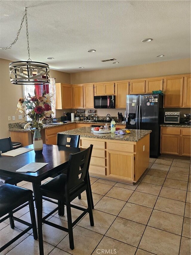 kitchen featuring a kitchen island, a textured ceiling, visible vents, black appliances, and light brown cabinets