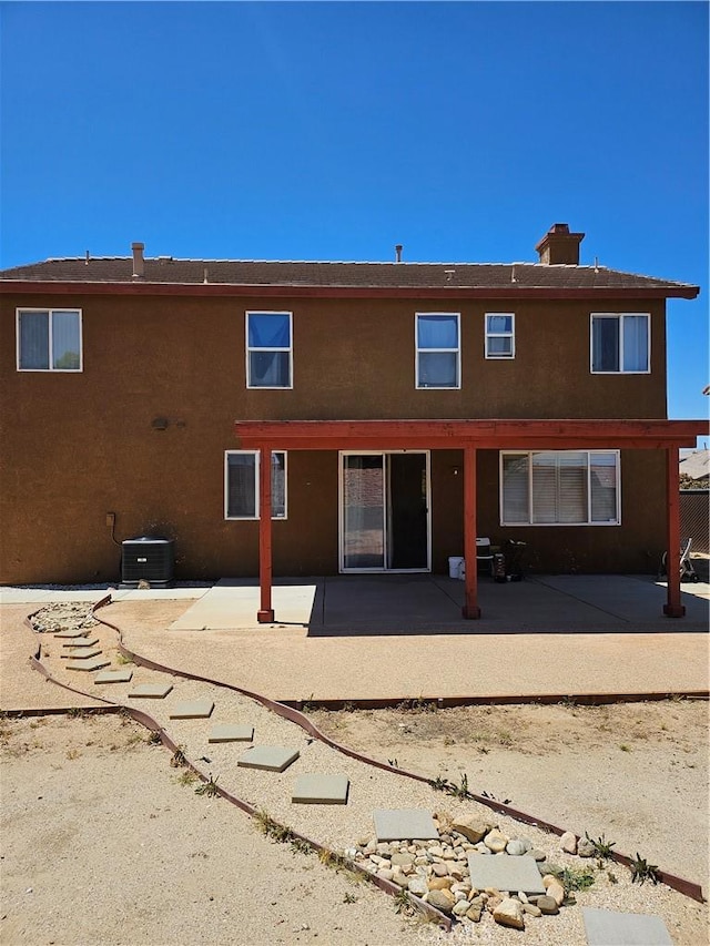 back of house with a patio, stucco siding, a chimney, and cooling unit