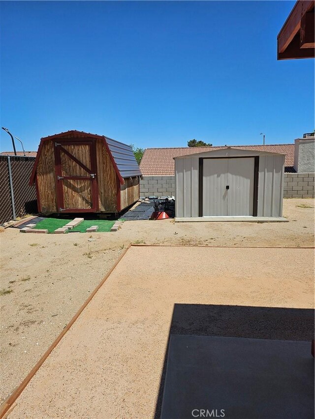 view of yard featuring fence, a storage unit, and an outdoor structure