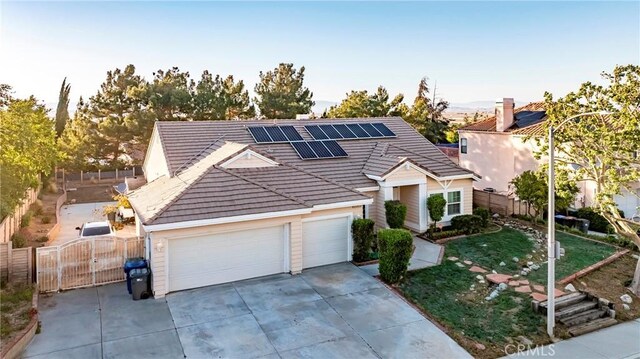 view of front of property with fence, a gate, concrete driveway, and solar panels