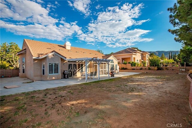 back of property featuring a tiled roof, a chimney, a patio area, a pergola, and stucco siding