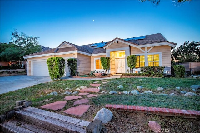 view of front of home with roof mounted solar panels, driveway, a front lawn, and a garage