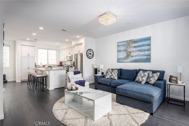 living room with dark wood-type flooring, baseboards, and recessed lighting