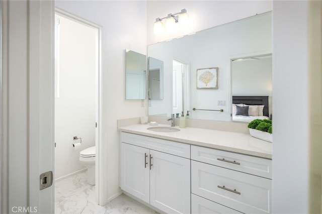 ensuite bathroom featuring marble finish flooring, toilet, and vanity
