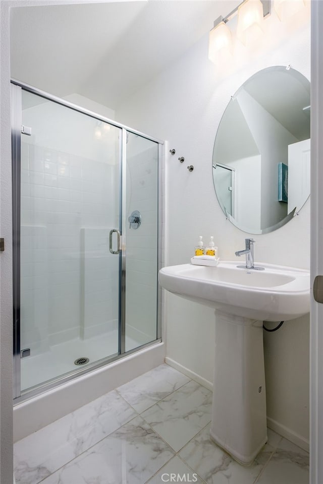 bathroom with marble look tile flooring, baseboards, and a stall shower