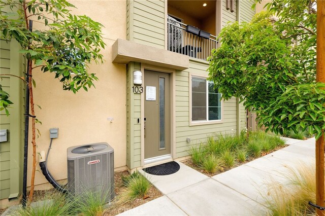 entrance to property with central AC unit and stucco siding