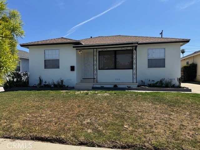 view of front of home with entry steps, a front yard, and stucco siding