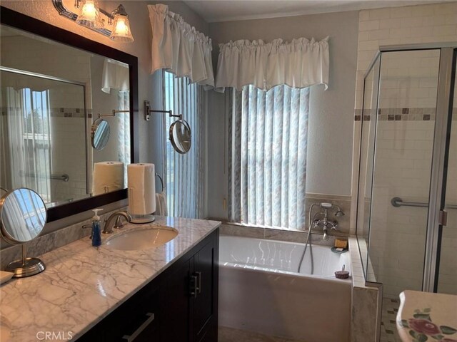full bathroom with vanity, a garden tub, and a stall shower