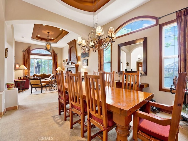 508 Lantern Crest Dr, Redlands, CA 92373 - dining room featuring a raised ceiling, light colored carpet, arched walkways, and a chandelier