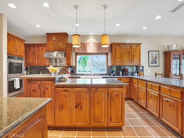 508 Lantern Crest Dr, Redlands, CA 92373 - kitchen featuring stainless steel double oven, brown cabinetry, decorative backsplash, under cabinet range hood, and visible vents