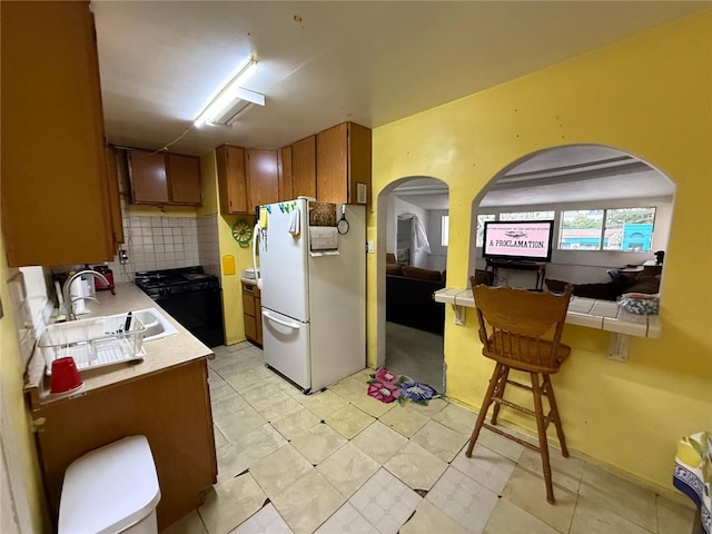 1380 Allison Ave, Los Angeles, CA 90026 - kitchen with freestanding refrigerator, range, brown cabinets, a sink, and arched walkways