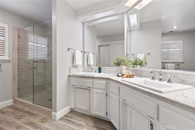 bathroom with a sink, double vanity, a stall shower, and wood finished floors