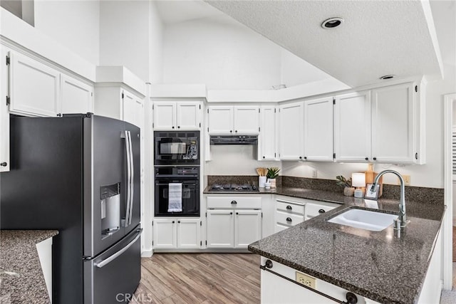 kitchen featuring white cabinets, ventilation hood, a sink, a peninsula, and black appliances