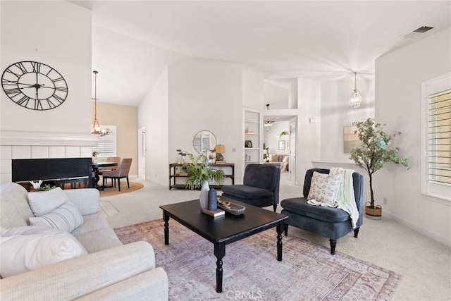 carpeted living room with high vaulted ceiling, visible vents, baseboards, and a notable chandelier