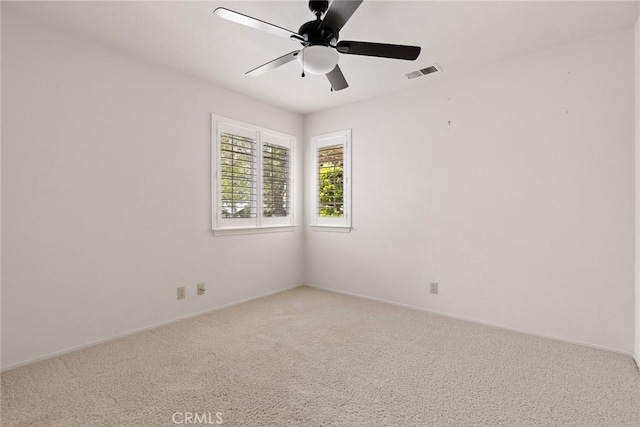 spare room with baseboards, a ceiling fan, light colored carpet, and visible vents