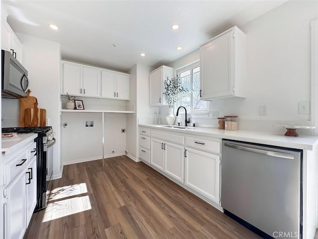kitchen with black microwave, dark wood finished floors, dishwasher, a sink, and gas range oven