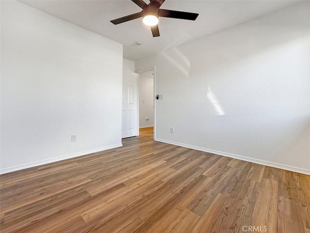 empty room featuring baseboards, a ceiling fan, and wood finished floors