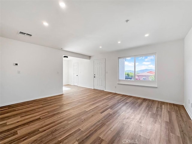 spare room with recessed lighting, baseboards, wood finished floors, and visible vents