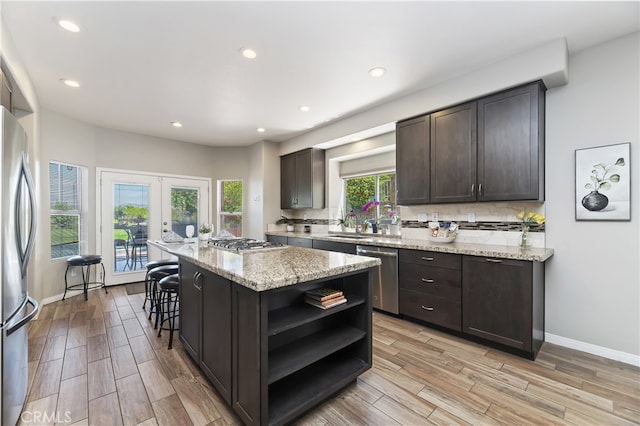 kitchen with open shelves, appliances with stainless steel finishes, french doors, and light wood finished floors