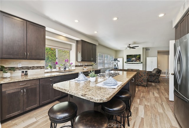 kitchen with dark brown cabinets, appliances with stainless steel finishes, a sink, and a kitchen bar