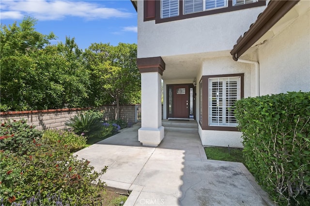doorway to property featuring fence and stucco siding
