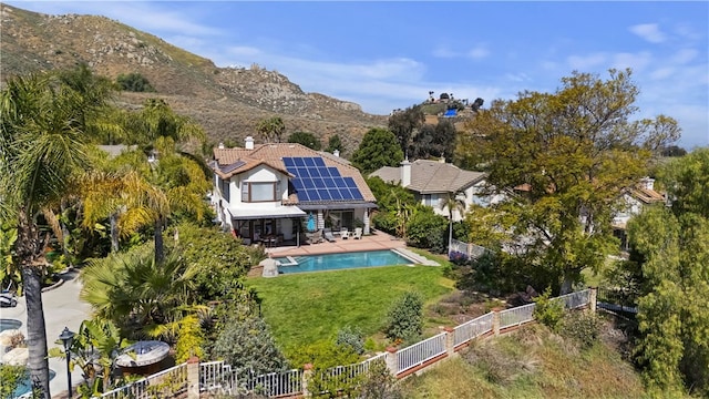 back of property featuring a fenced backyard, a fenced in pool, roof mounted solar panels, a patio area, and a lawn