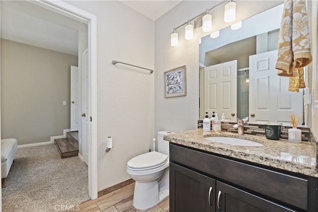 full bath featuring vanity, baseboards, wood finished floors, and toilet