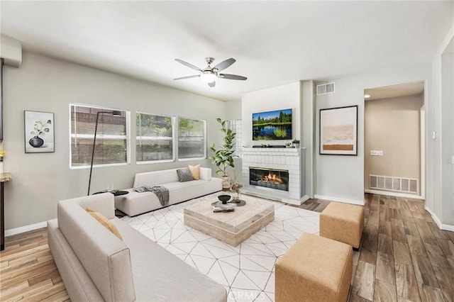 living room with baseboards, a ceiling fan, visible vents, and wood finished floors