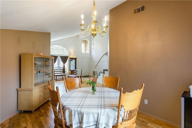 dining room featuring visible vents, wood finished floors, baseboards, an inviting chandelier, and stairs