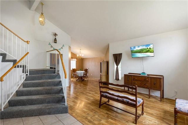 stairs with an inviting chandelier, high vaulted ceiling, baseboards, and wood finished floors
