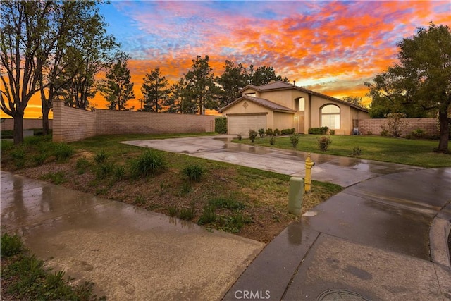 exterior space featuring a garage, fence, a yard, concrete driveway, and stucco siding