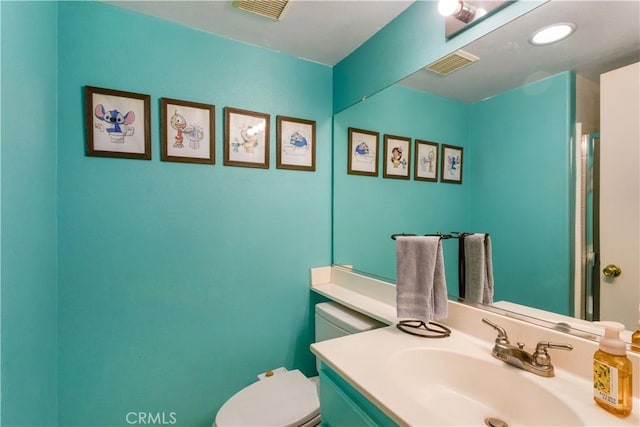 half bathroom featuring vanity, toilet, and visible vents