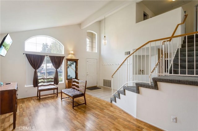 living area featuring high vaulted ceiling, stairs, wood finished floors, and visible vents