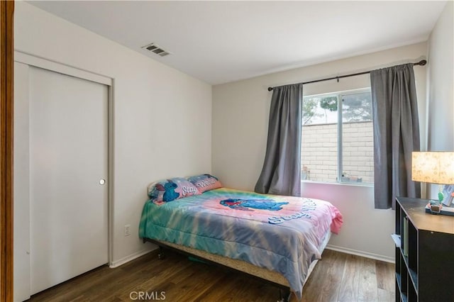 bedroom with baseboards, visible vents, and wood finished floors