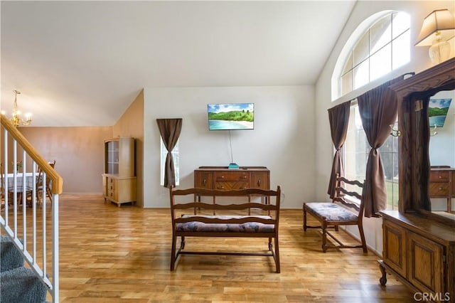 living area featuring light wood-style flooring, stairs, lofted ceiling, and a chandelier