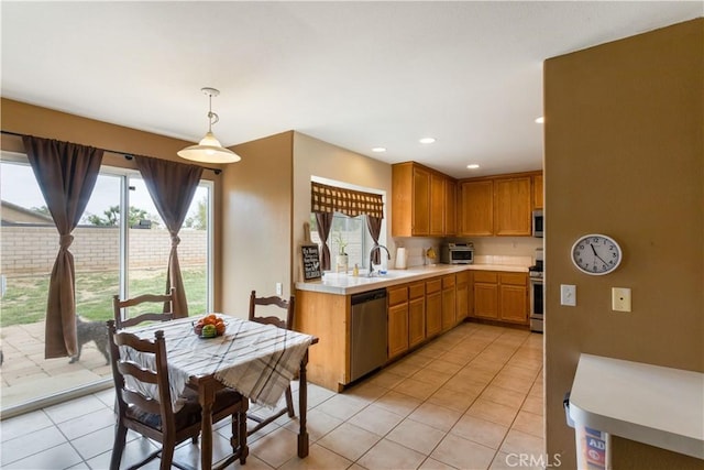 kitchen featuring decorative light fixtures, light tile patterned floors, light countertops, a sink, and stainless steel appliances