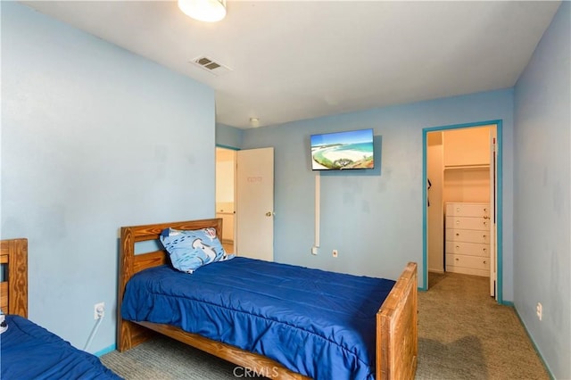 bedroom with carpet floors, baseboards, a walk in closet, and visible vents