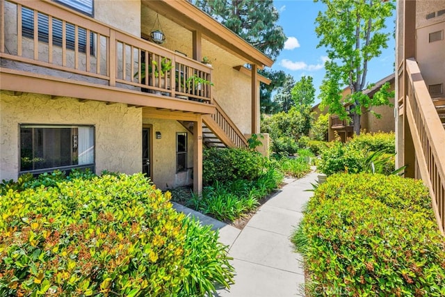 view of side of property with stucco siding, stairway, and a deck
