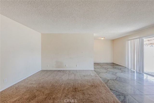spare room featuring a textured ceiling and baseboards
