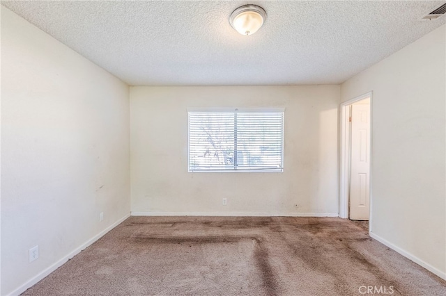 carpeted spare room with baseboards, a textured ceiling, and visible vents