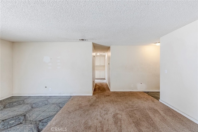 carpeted empty room with visible vents, a textured ceiling, and baseboards