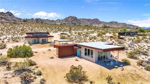 rear view of property featuring view of desert, a mountain view, a rural view, and a patio