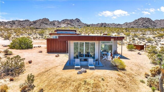 back of house with a mountain view, a patio area, and a desert view