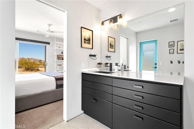 bathroom with double vanity, a ceiling fan, visible vents, speckled floor, and a sink