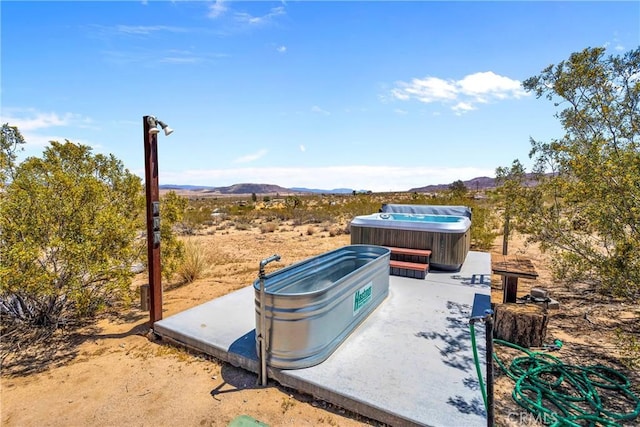 view of patio with a mountain view and a hot tub