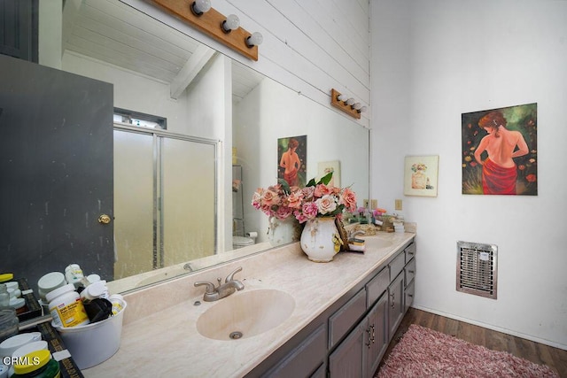 full bath with double vanity, visible vents, a stall shower, wood finished floors, and a sink